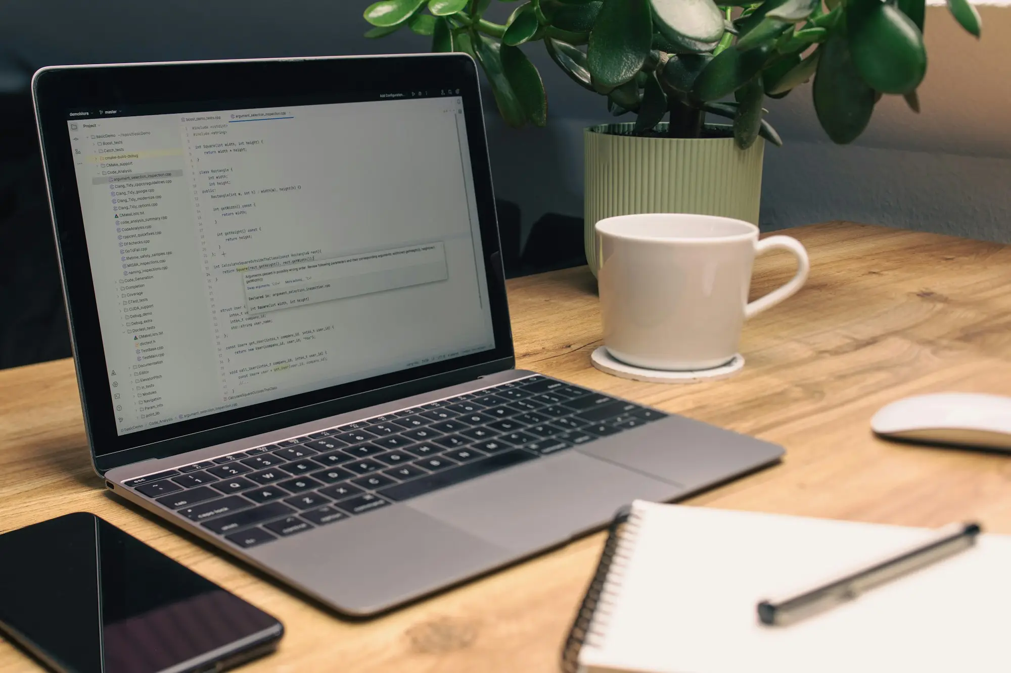 Laptop, notebook, phone and mug on a tidy desk