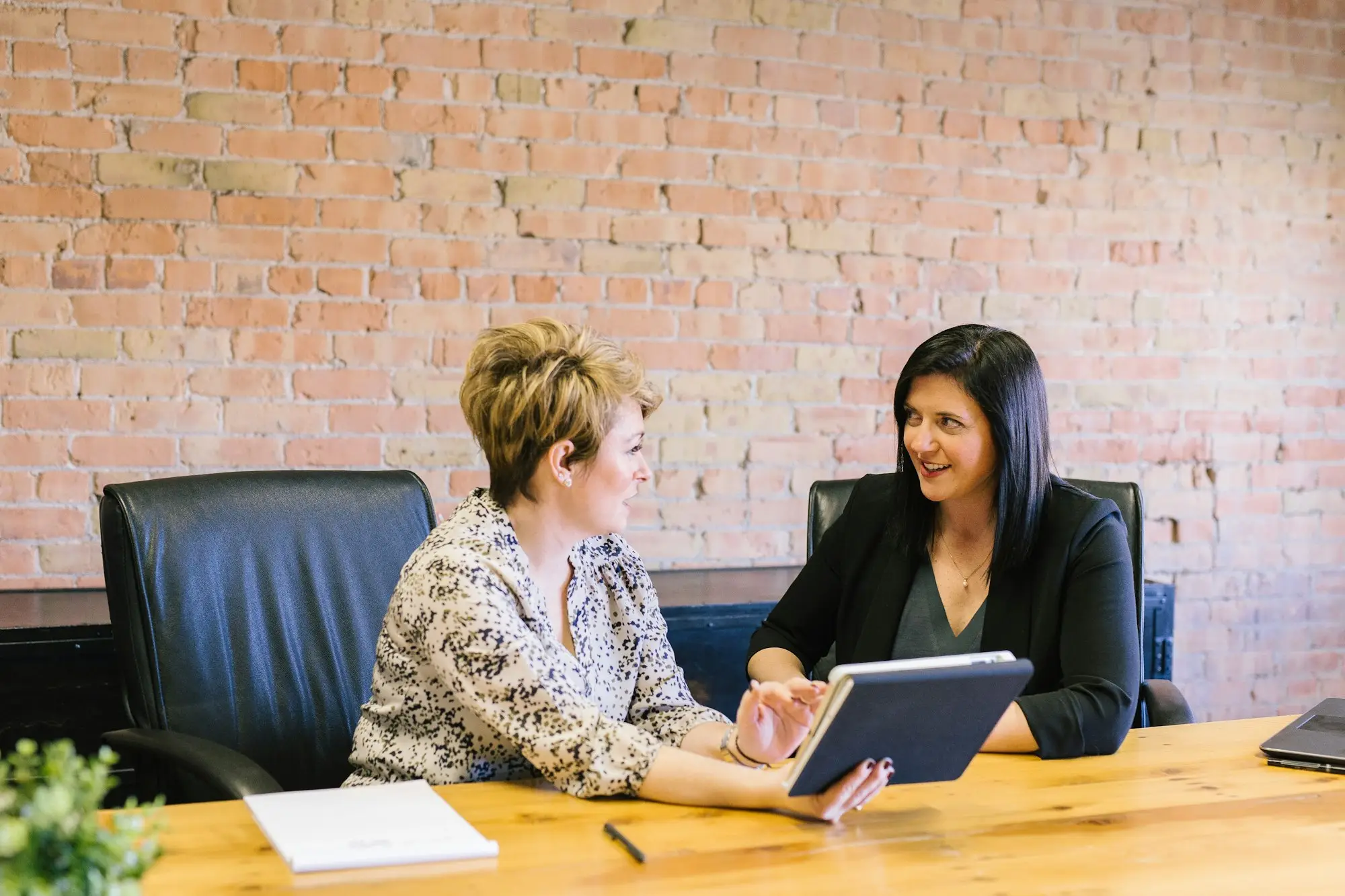 Two women talking through paperwork at a meeting table